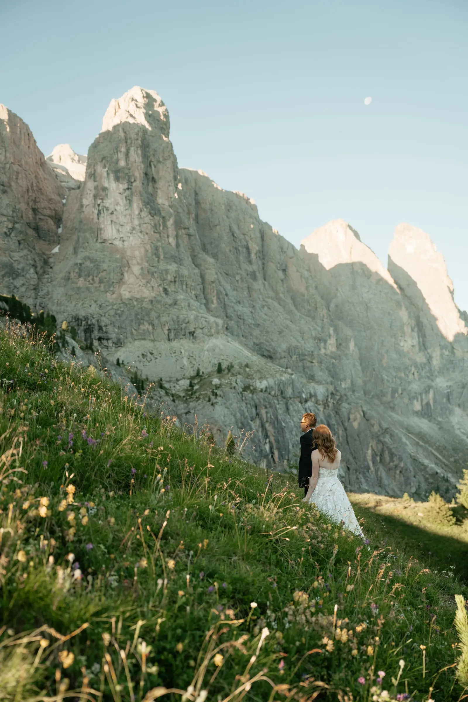 Couple small on a flower meadow below the towering Dolomites
