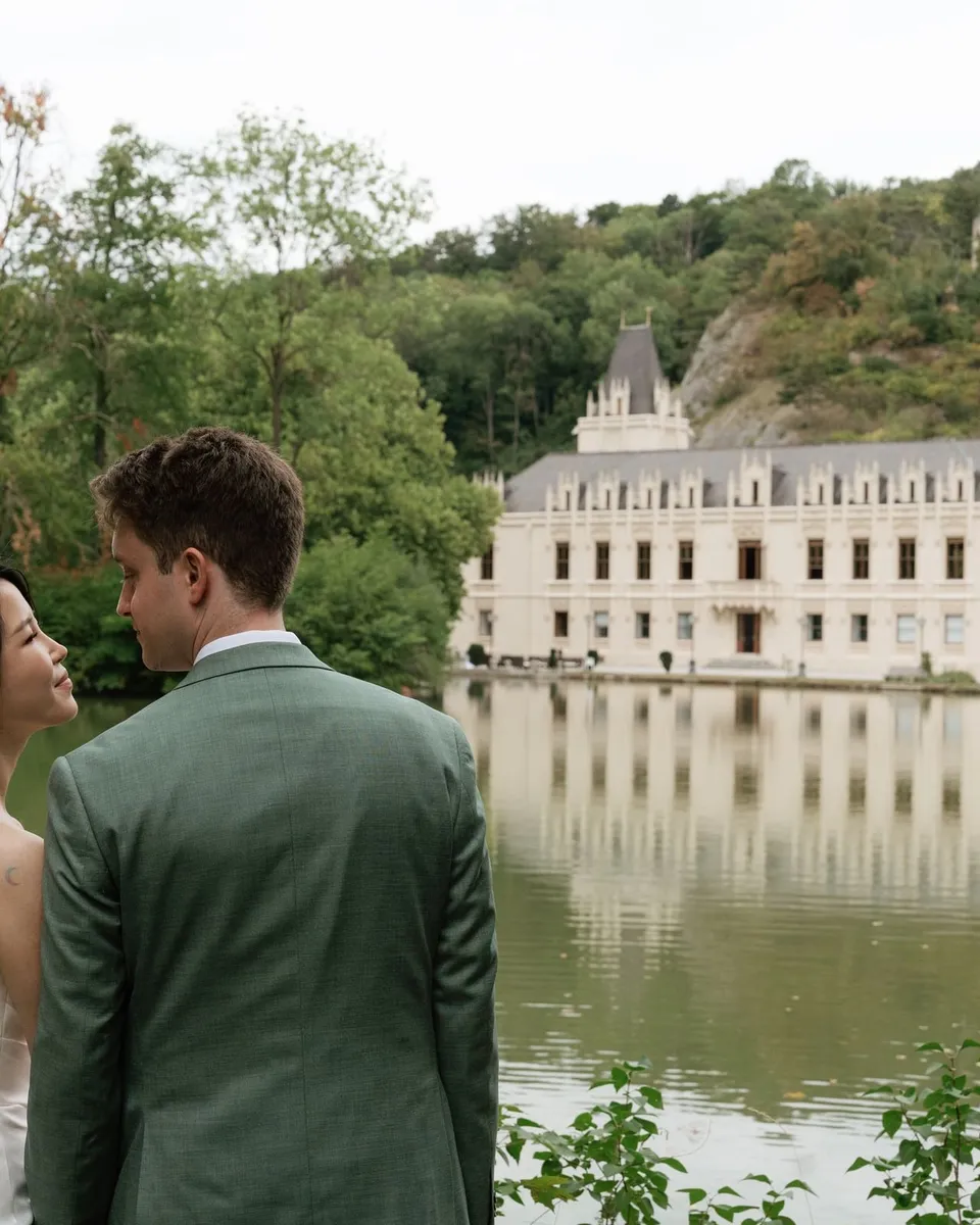 Bride and groom by the lake with Schloss Hernstein reflected in the water