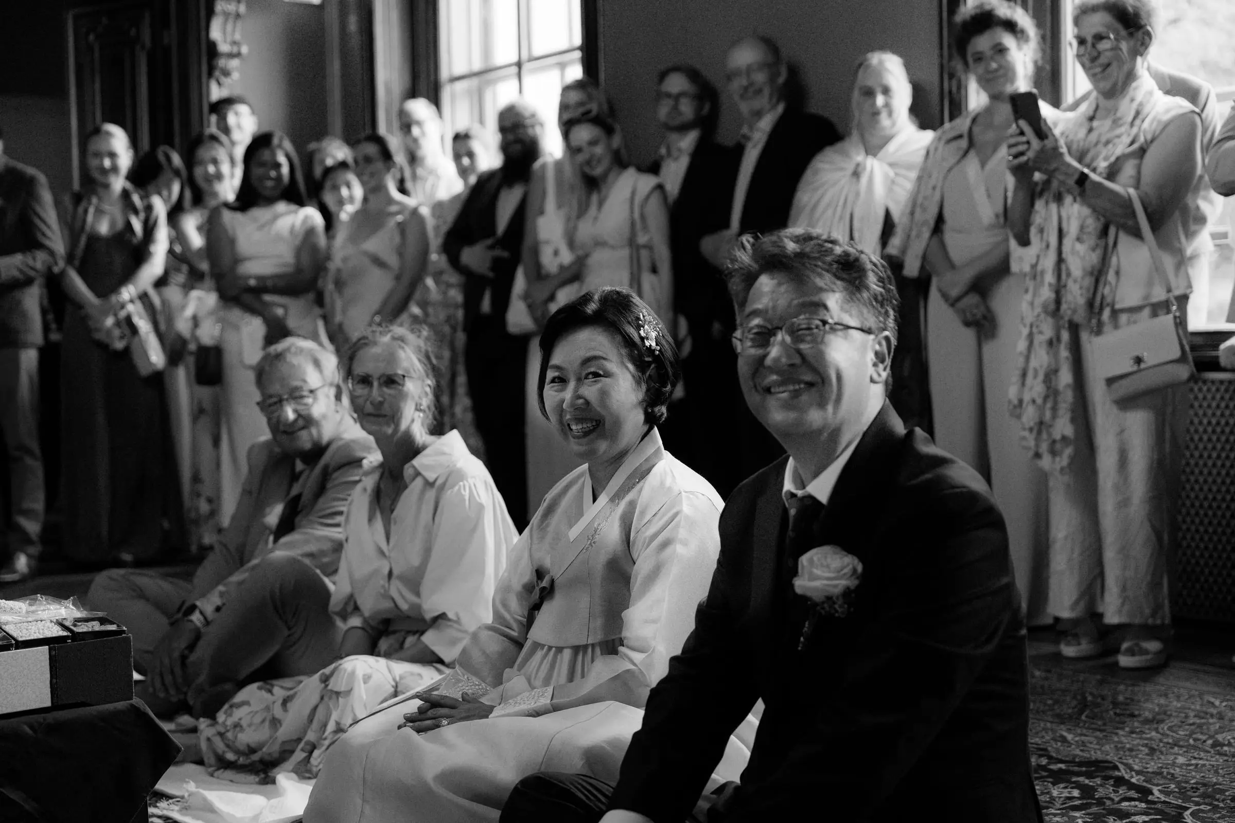 Black and white photo of family and guests smiling in the castle hall