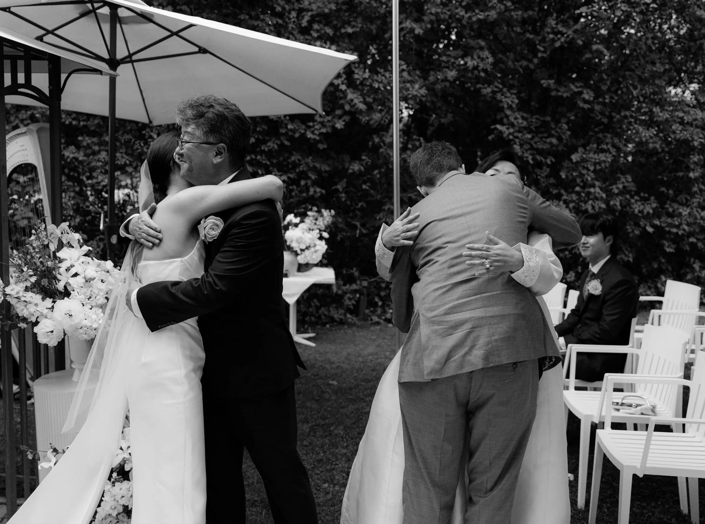 Black and white photo of the couple hugging guests after the ceremony