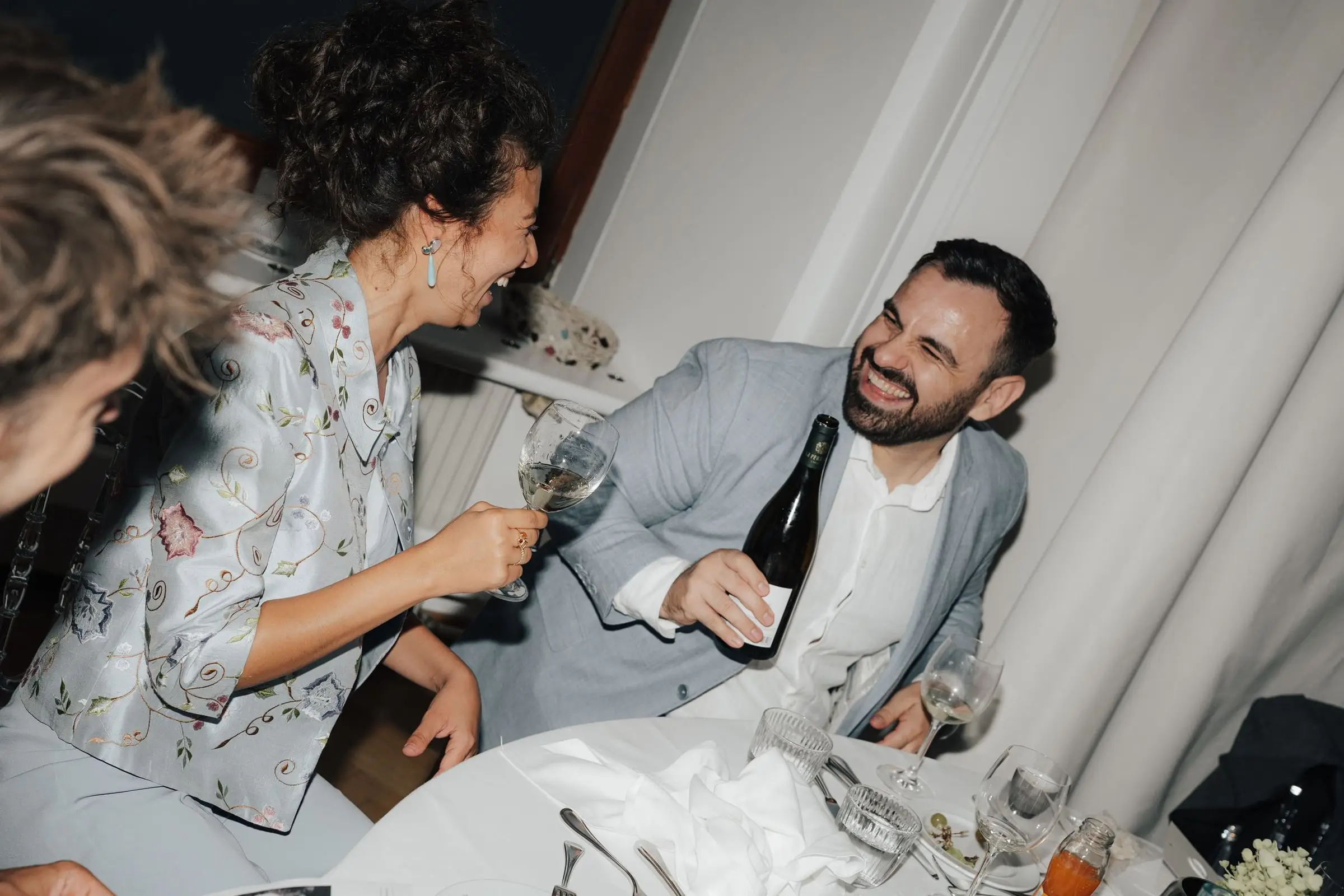Guests laughing and raising glasses at the dinner table