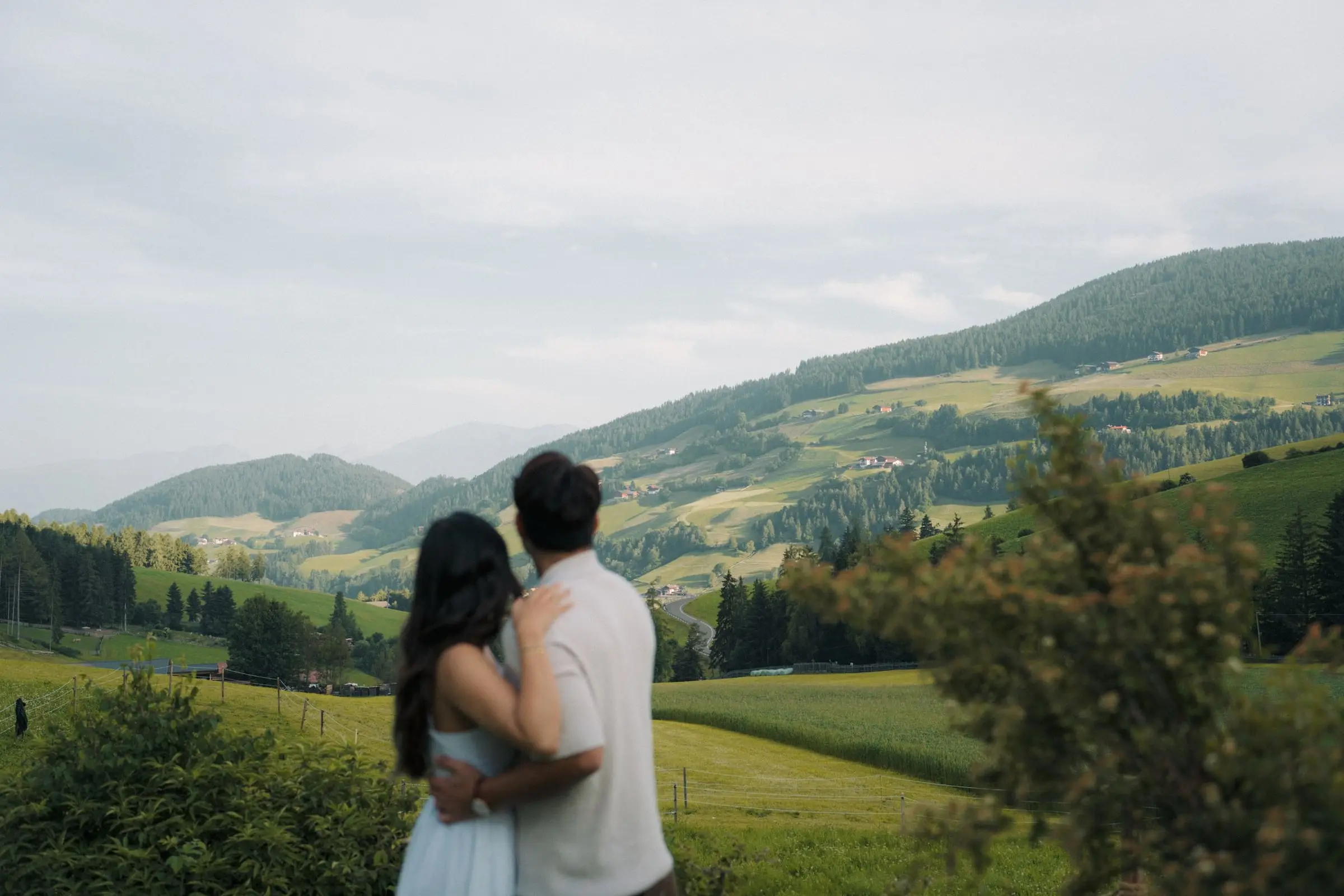 Couple seen from behind looking over the green hills of Val di Funes
