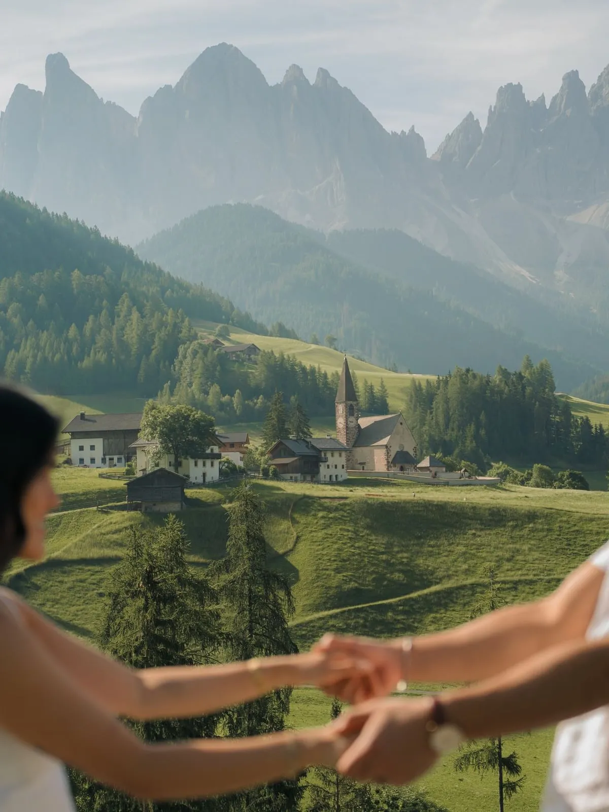 Couple holding hands above Santa Maddalena village and the Odle peaks