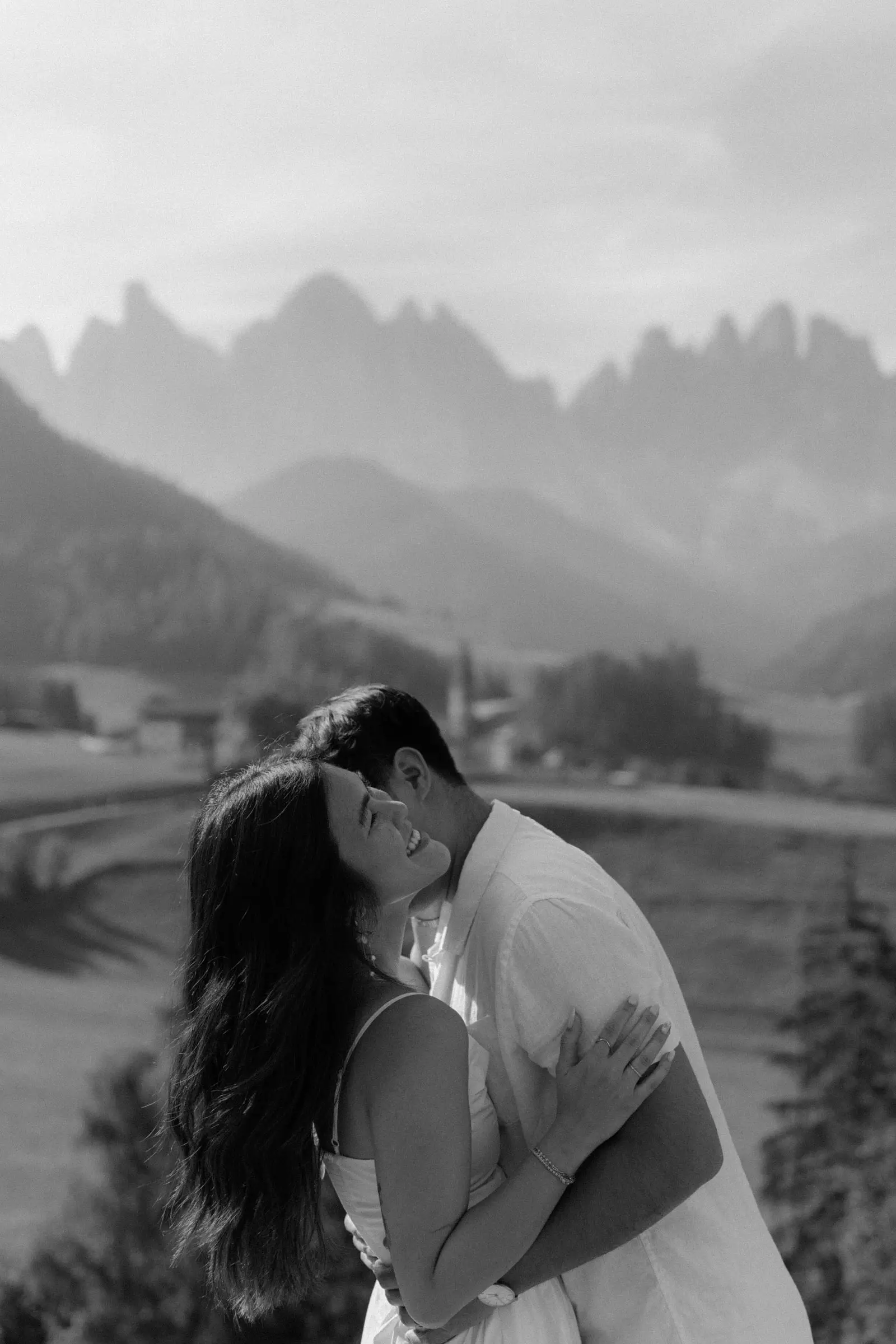 Black and white photo of the couple embracing with the Odle peaks behind