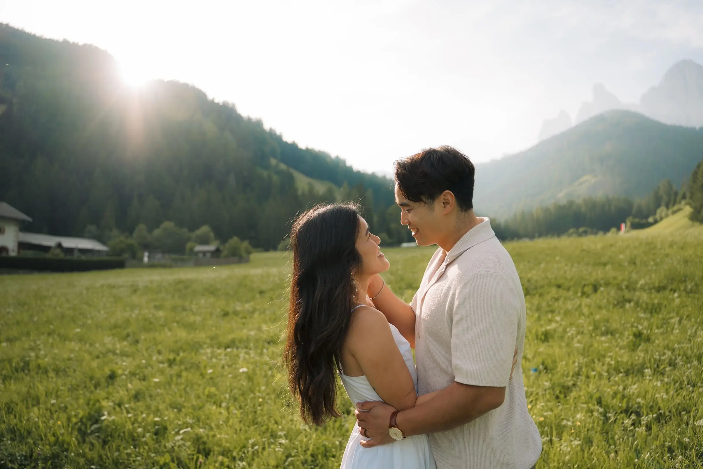 Couple smiling at each other in a sunlit meadow