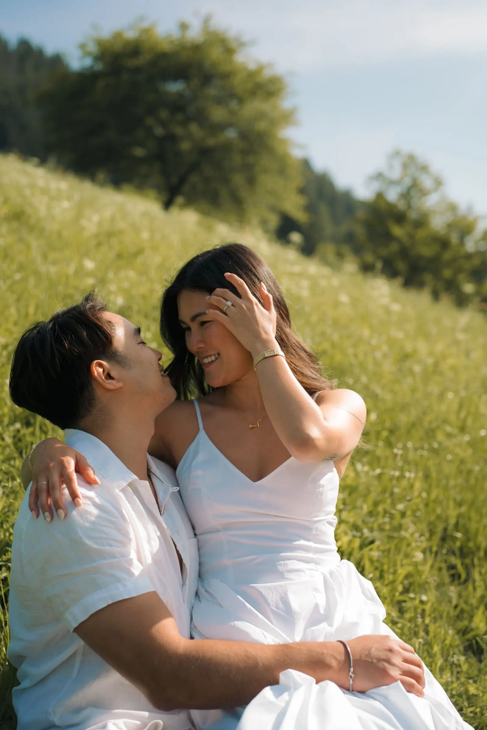 Couple sitting in the grass, laughing, on a hillside in Val di Funes