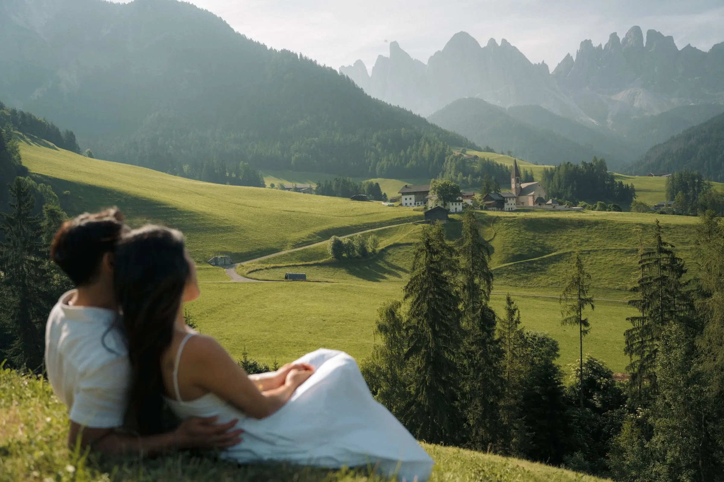 Couple resting in the grass looking over Val di Funes
