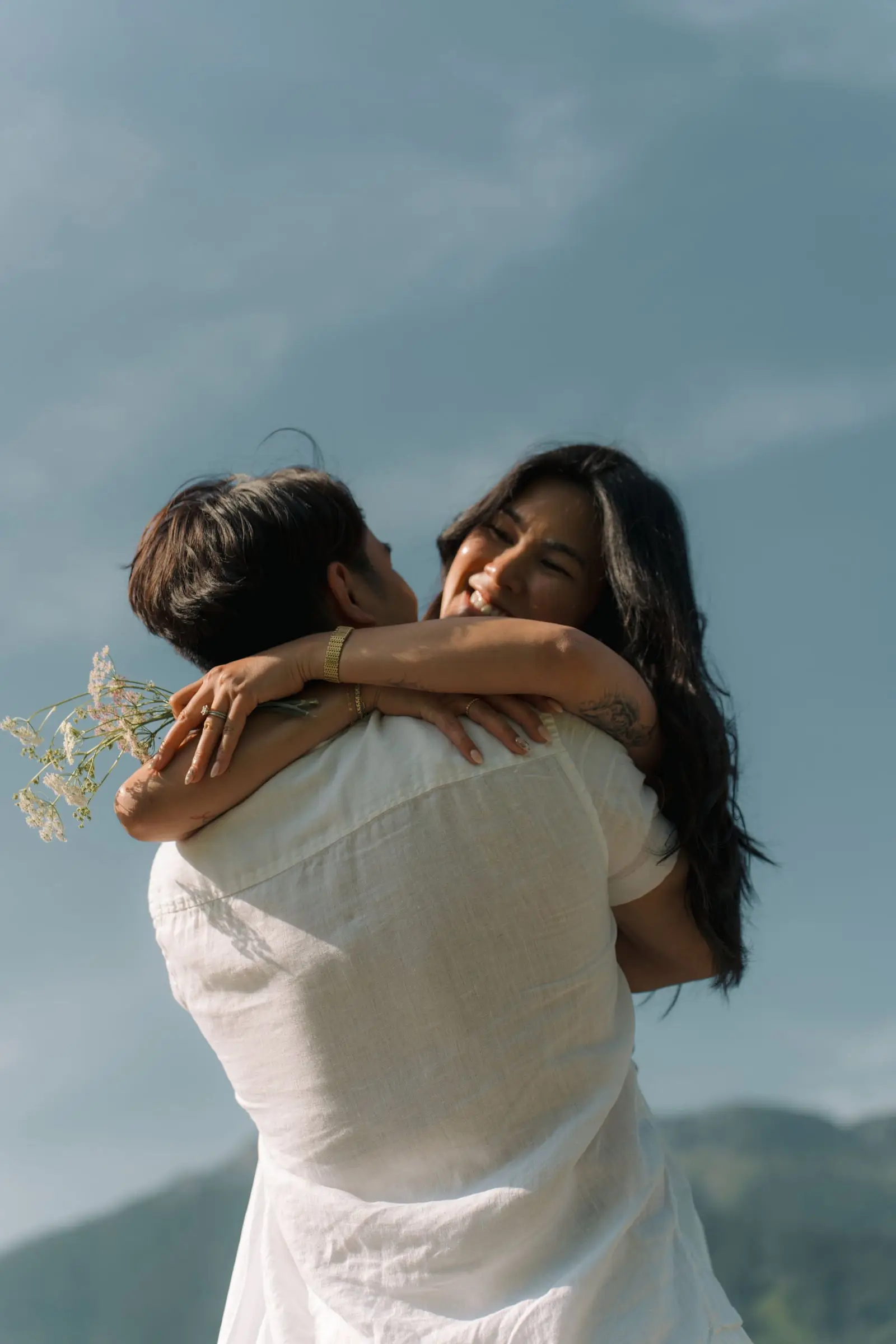 Couple hugging tightly against a blue sky
