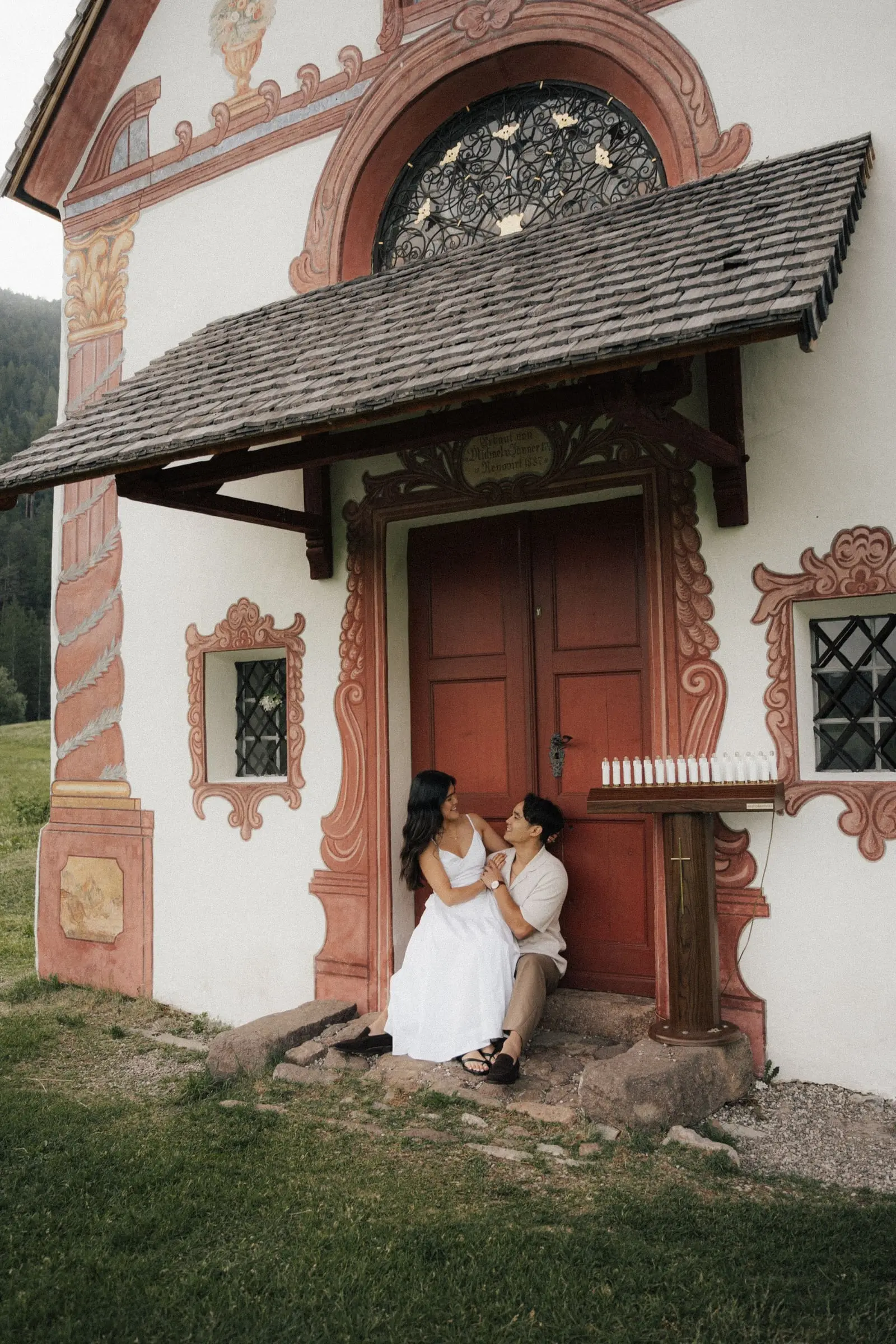 Couple sitting in the painted doorway of St. John's Chapel in Ranui