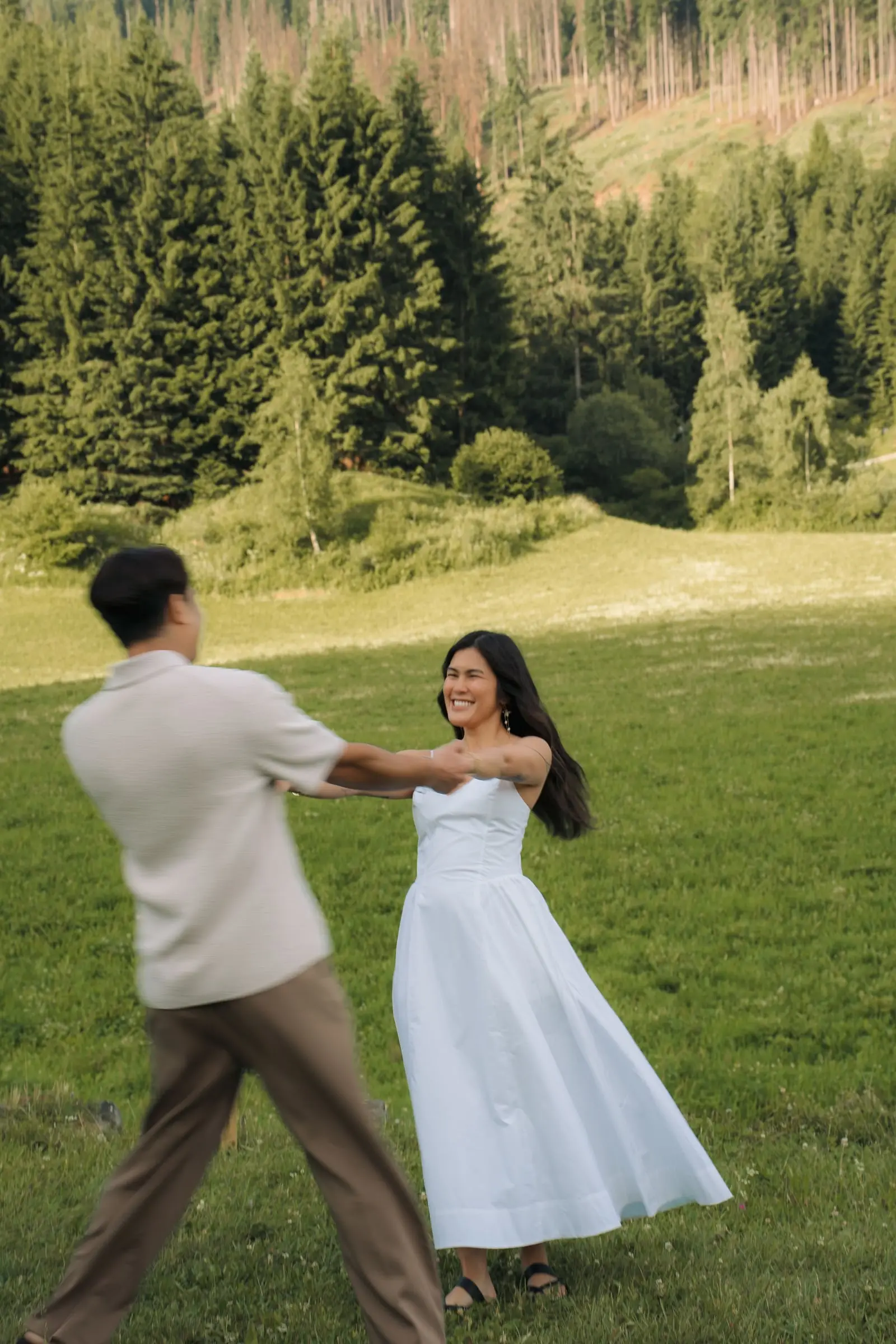 He twirls her in her white dress in a meadow