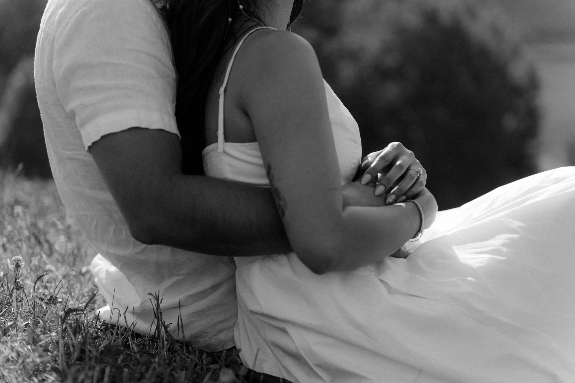 Black and white detail of the couple holding each other in the grass
