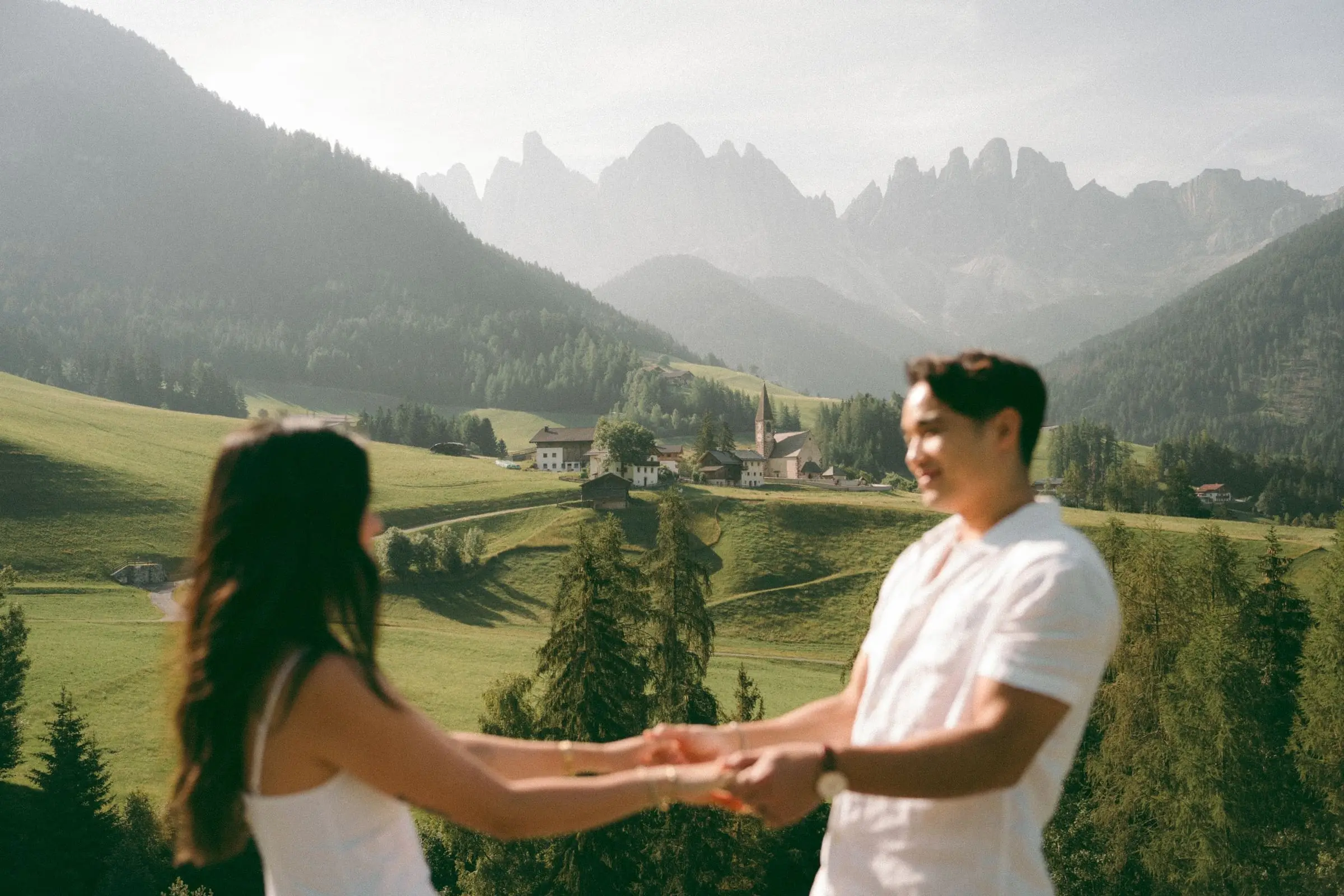 Couple holding hands above the valley and the Odle peaks