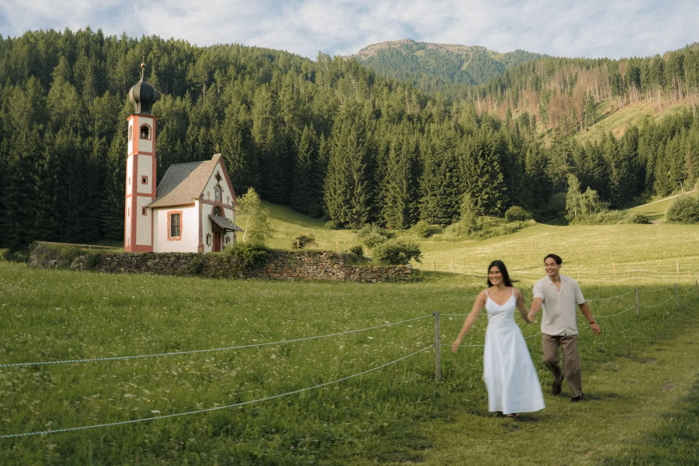 Couple walking through the meadow near St. John's Chapel in Ranui