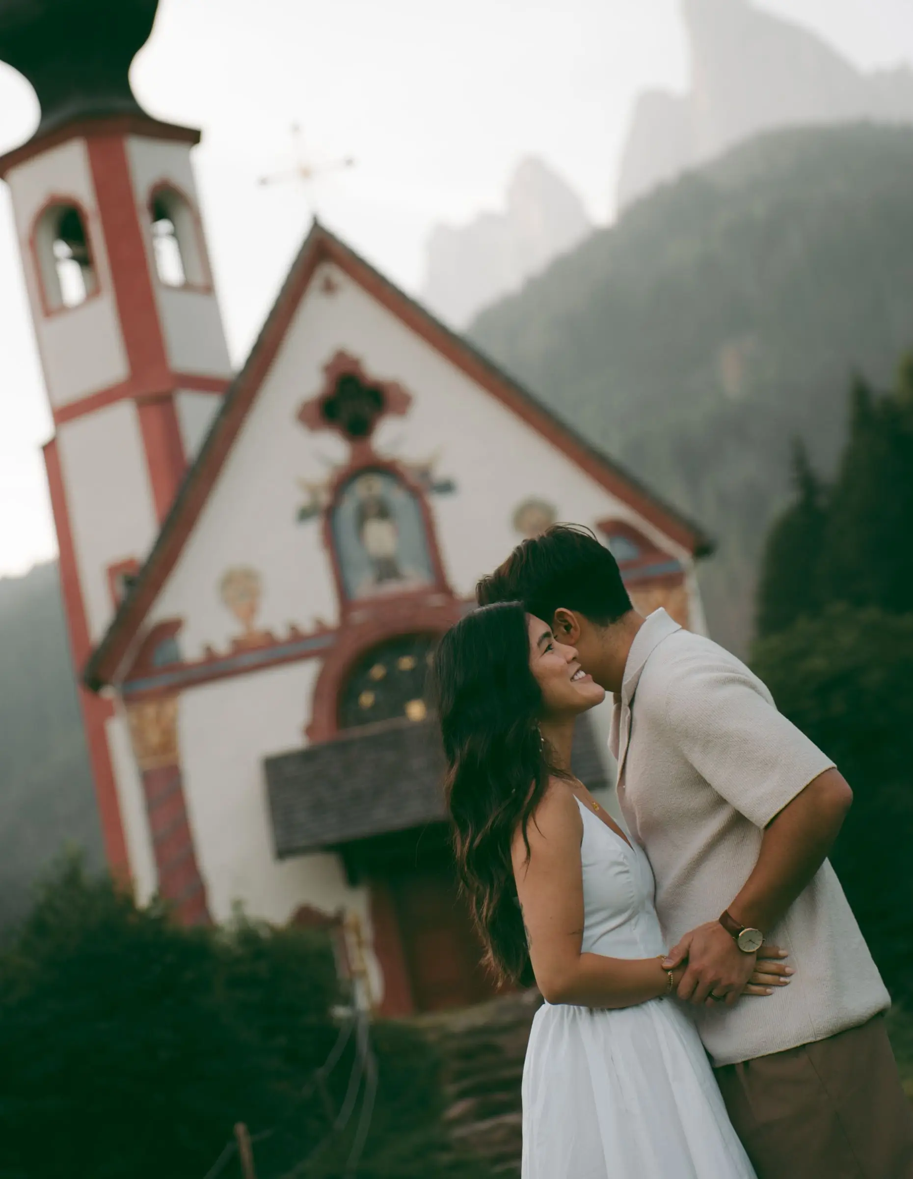 Couple kissing in front of the painted facade of St. John's Chapel